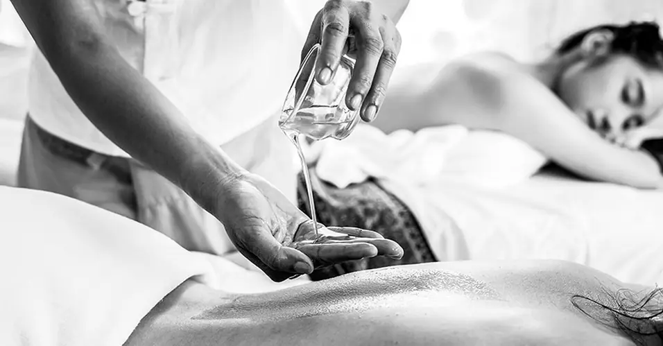 Warmes Aromaöl wird über die Hand der Therapeutin gegossen